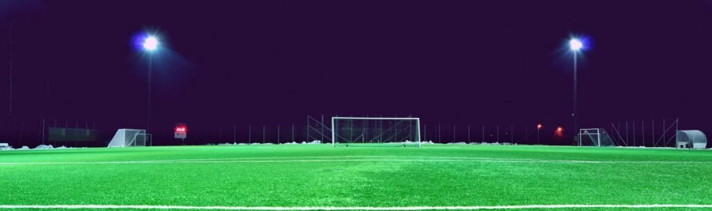 A brightly lit soccer field at night in Norrtälje, Sweden, showcasing green turf and stadium lights.